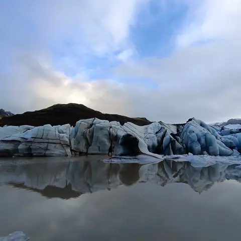 Blocchi di ghiaccio azzurri riflessi nell'acqua di una laguna glaciale in Islanda