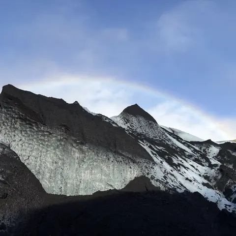 Arcobaleno sopra una montagna innevata vicino al ghiacciaio in Islanda
